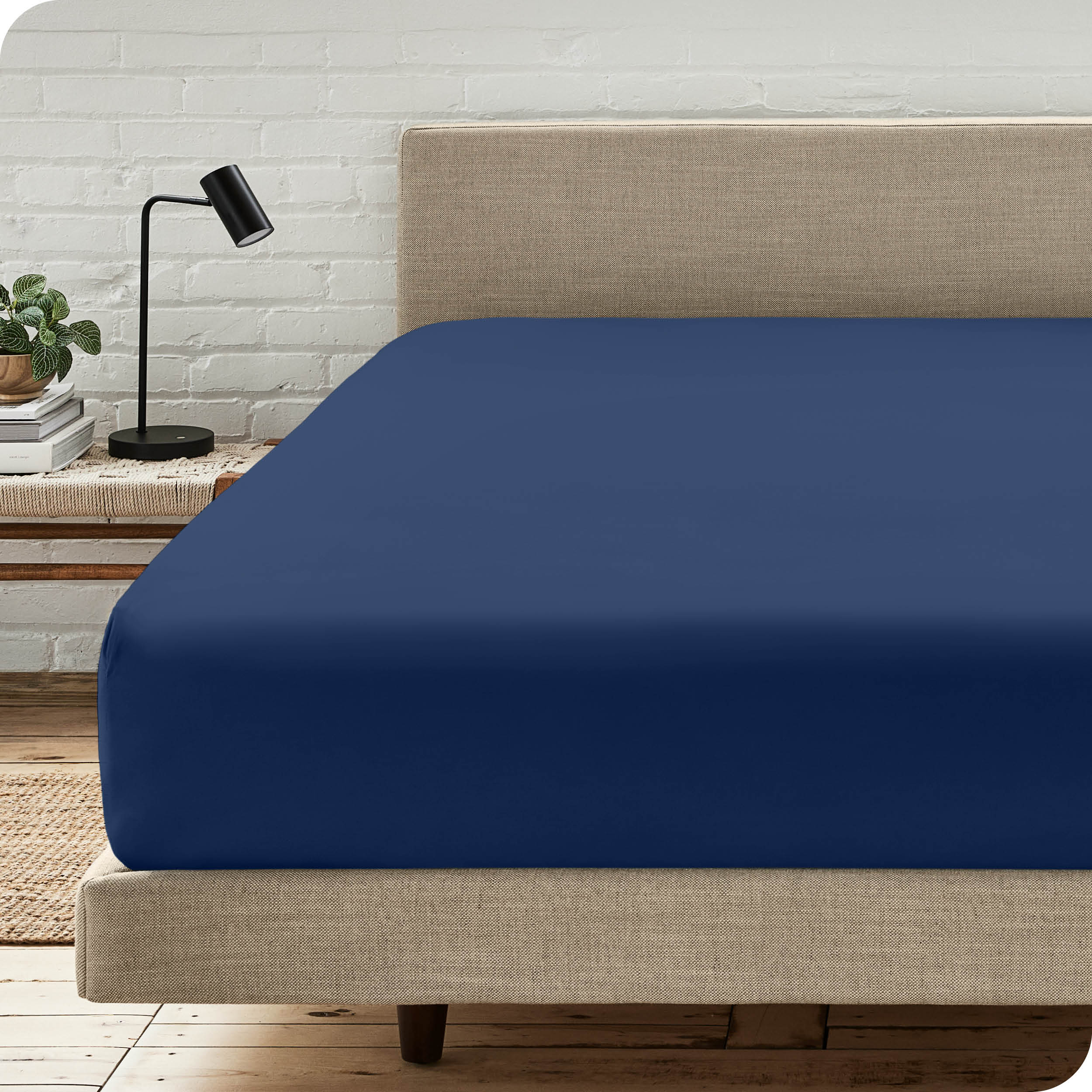 A bed with a microfiber fitted sheet on the mattress. 