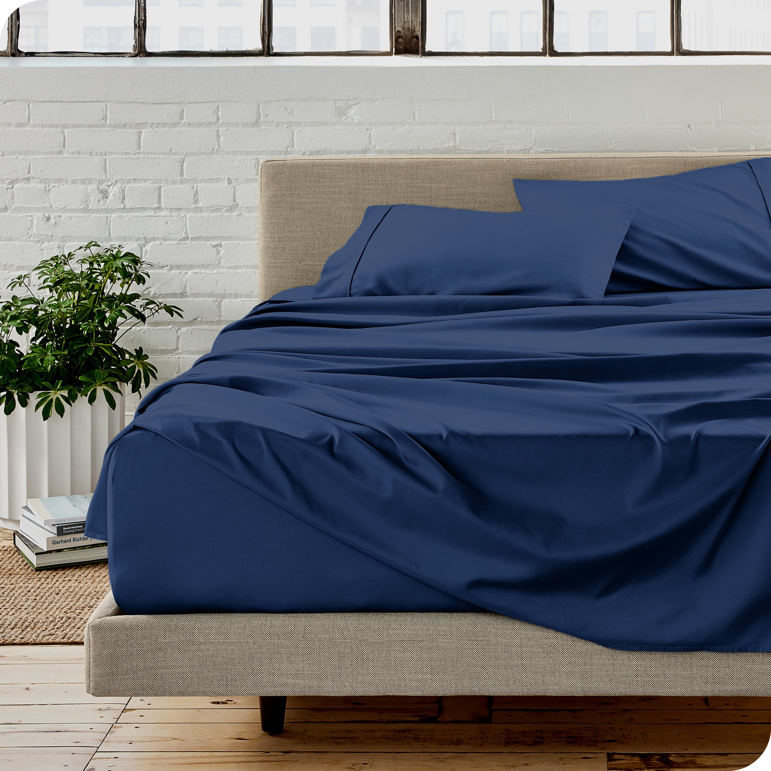 Microfiber sheets on a bed with a brick wall behind it
