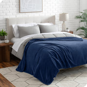 A textured microplush blanket is draped over a bed made with grey duvet set