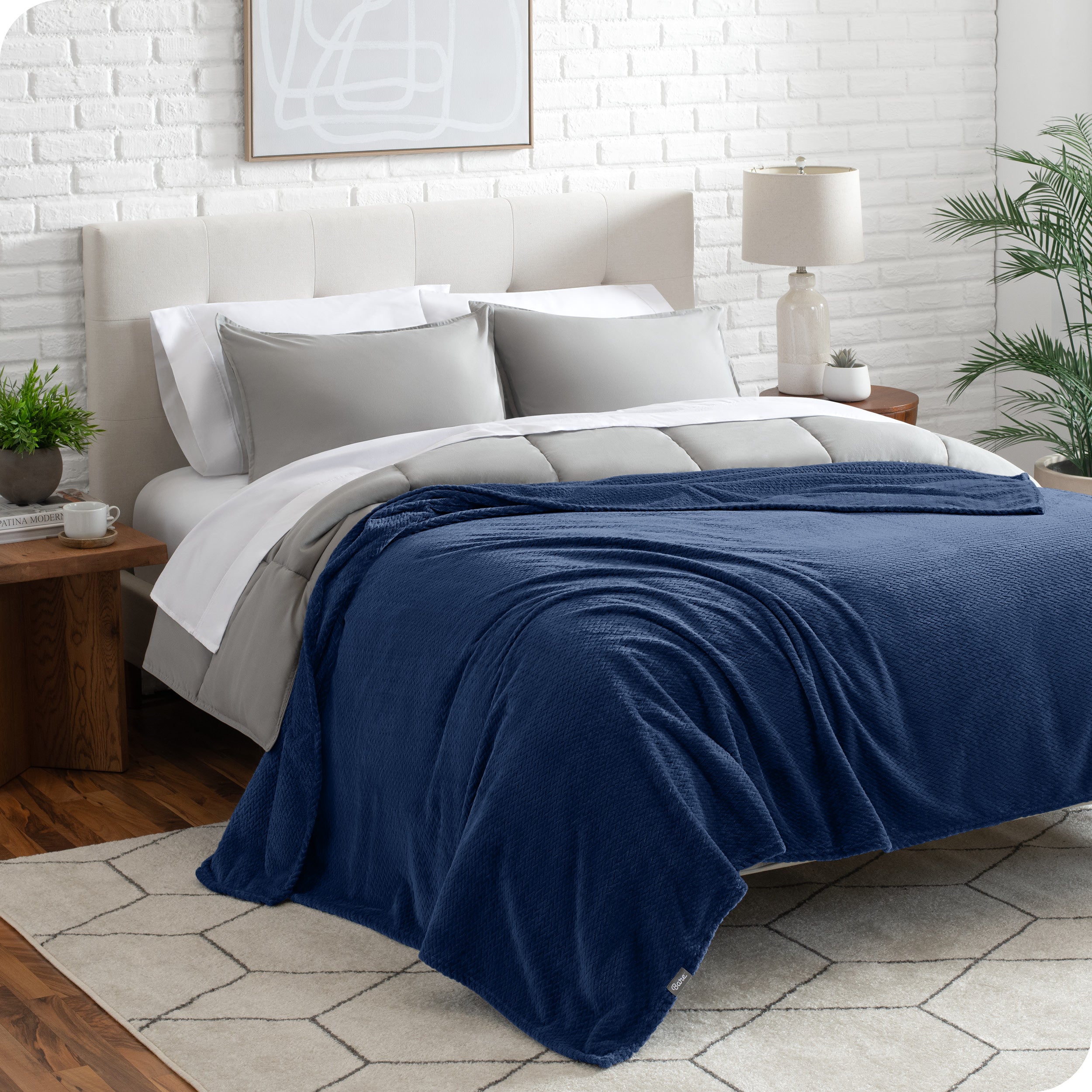 A textured microplush blanket is draped over a bed made with grey duvet set