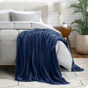 A textured microplush blanket is hanging over the corner of a bed