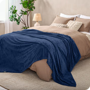 A microplush blanket spread out over the end of a bed