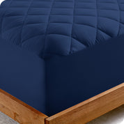 The corner of a bed showing the texture of the quilted mattress pad.

