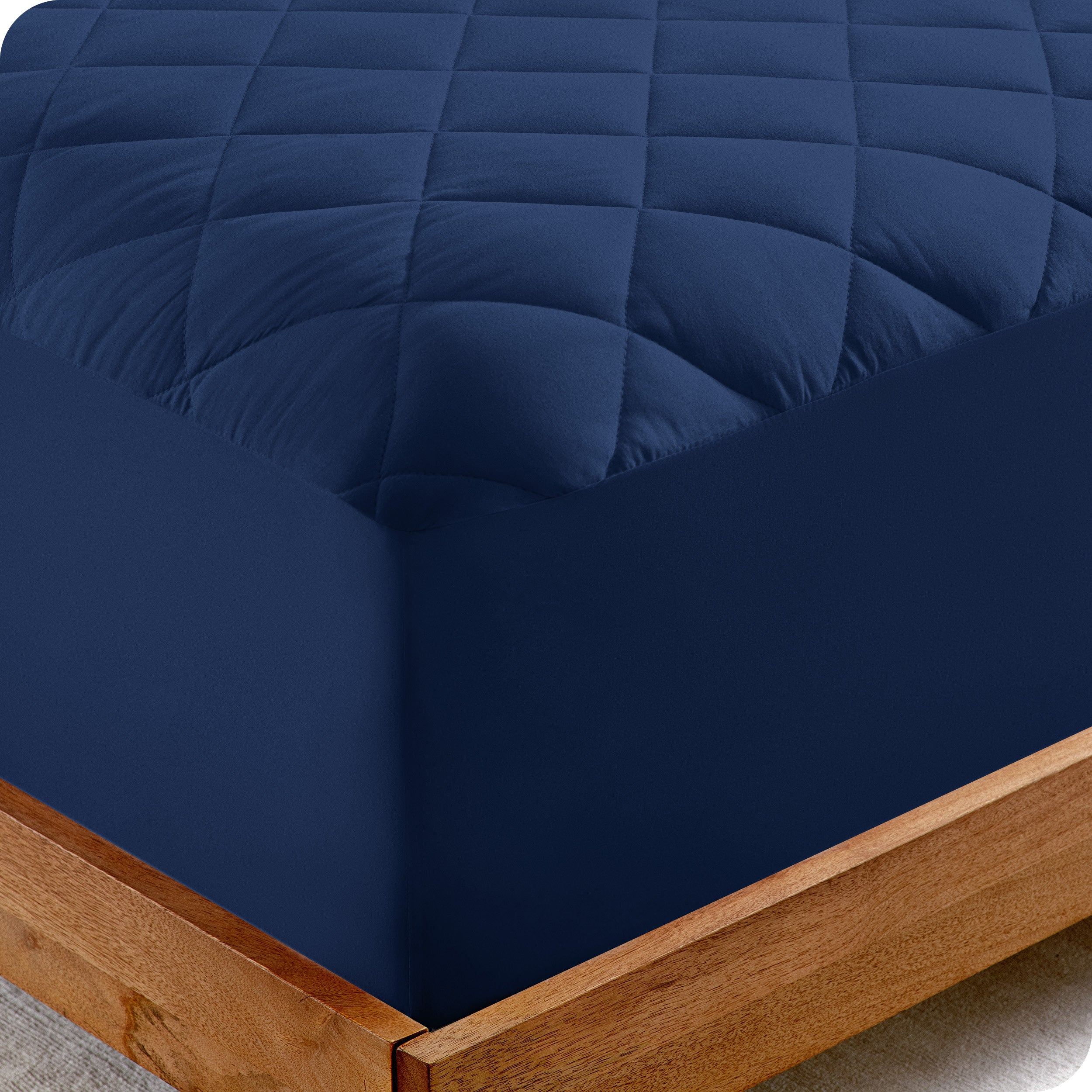 The corner of a bed showing the texture of the quilted mattress pad.
