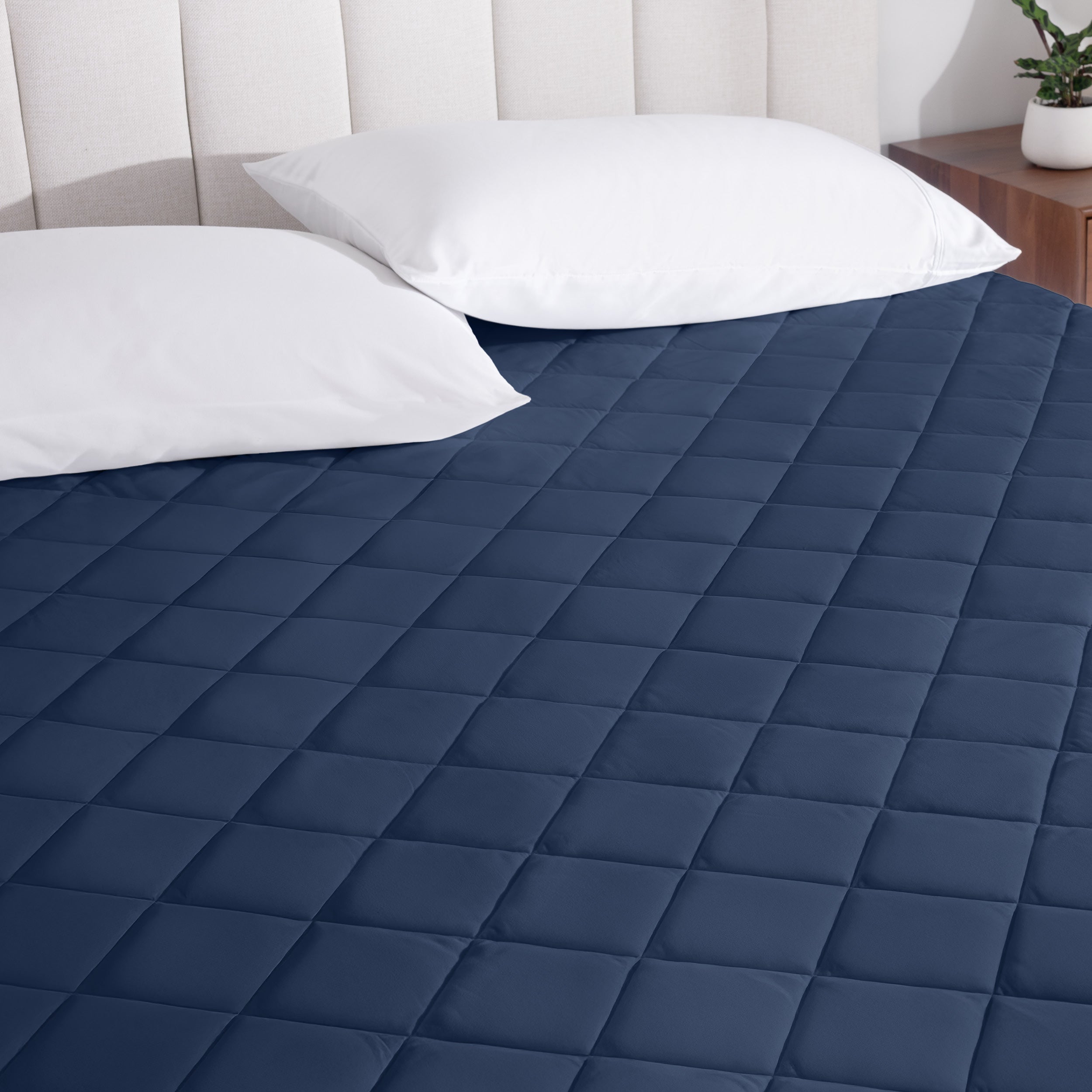A mattress pad on a bed with two pillows from above.