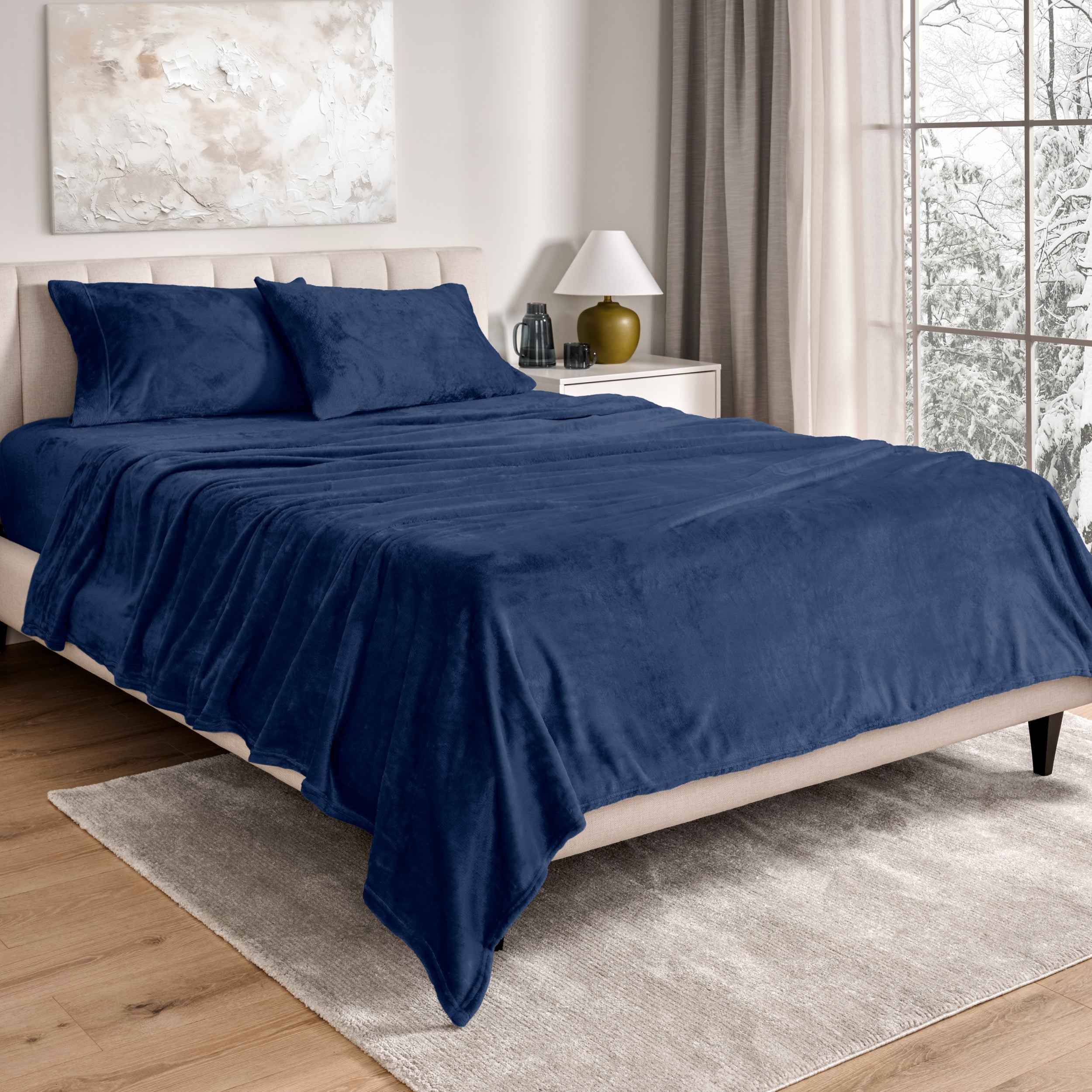 Sheets and matching pillowcases on a bed in a bedroom with a lamp and window in the background.