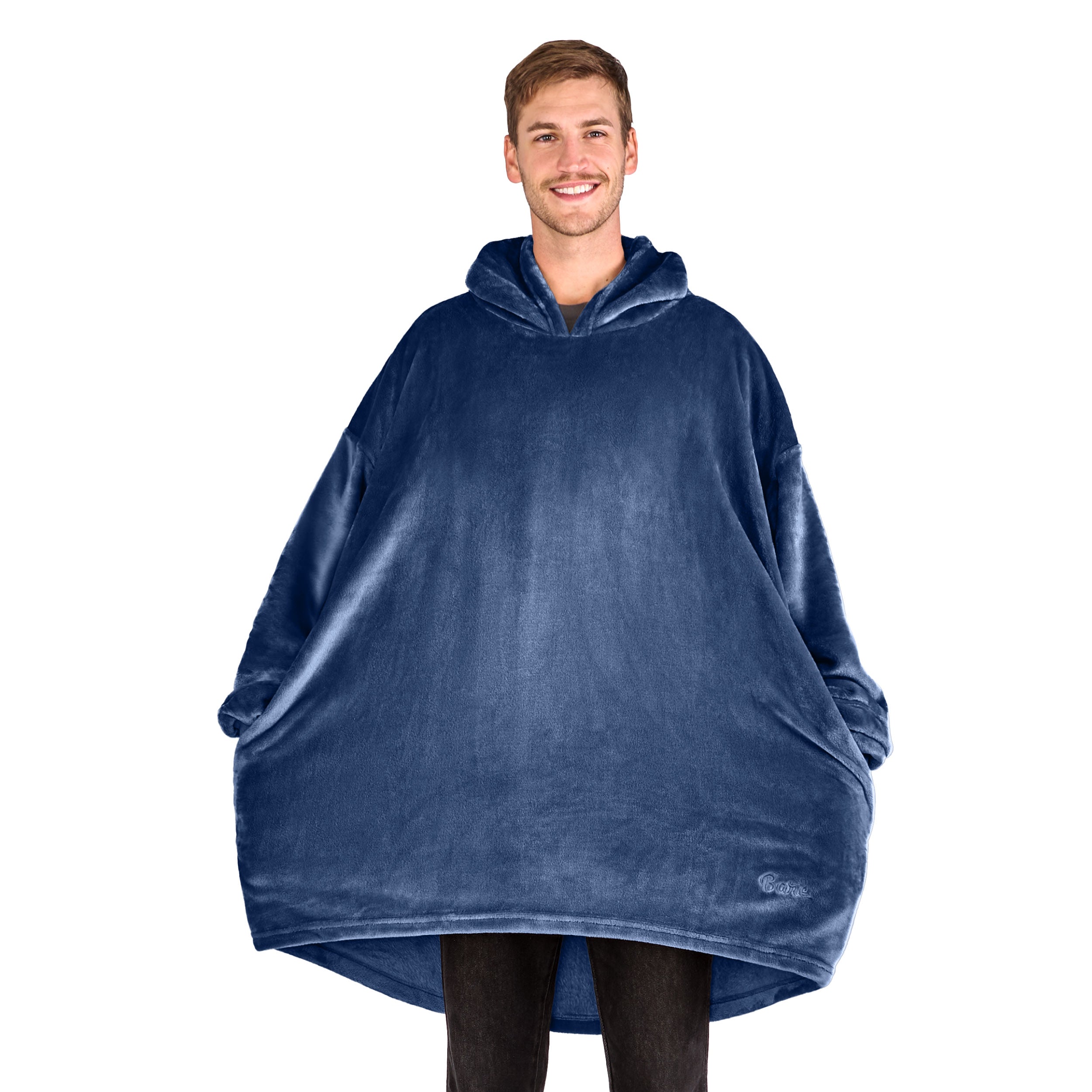A man has a microplush wearable blanket on and his hands are in the side pockets