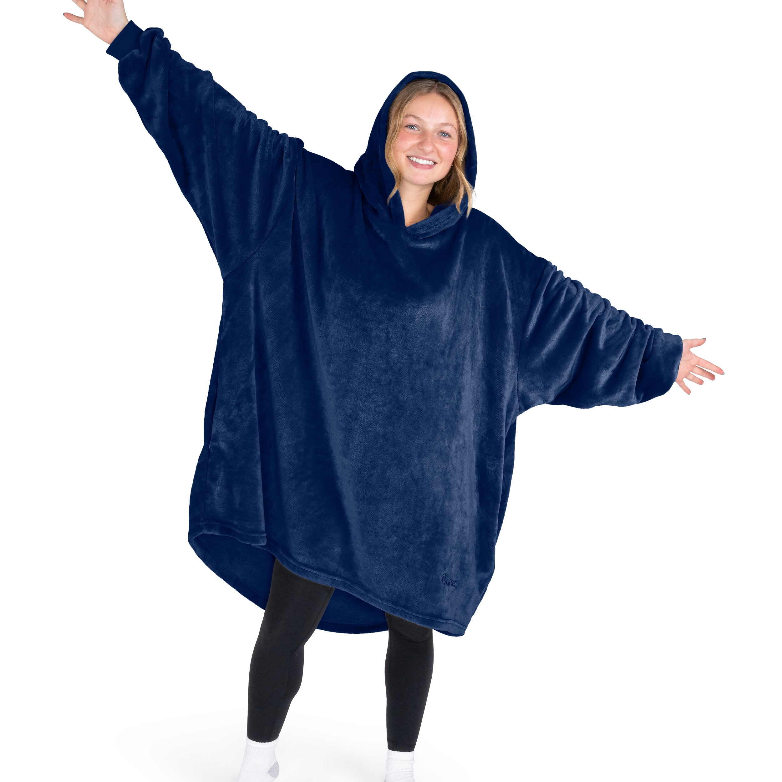 A woman is standing with her arms stretched out and has a hooded wearable blanket on