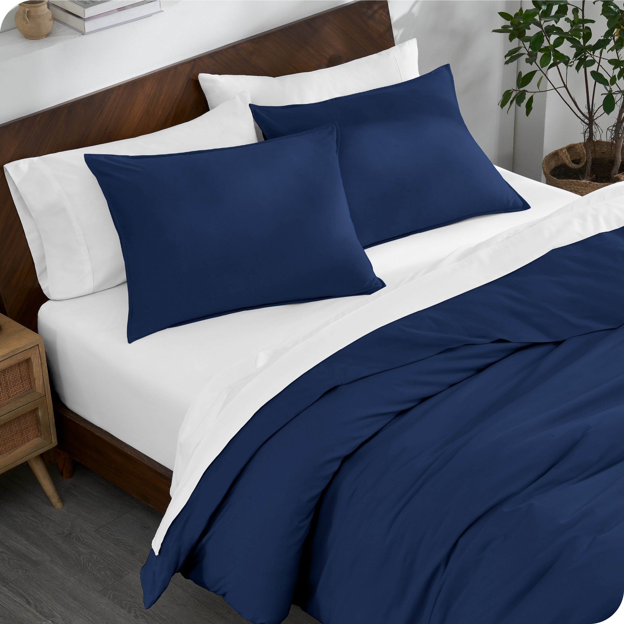 A bed made with an organic jersey duvet cover, pillow sham covered pillows and extra pillows