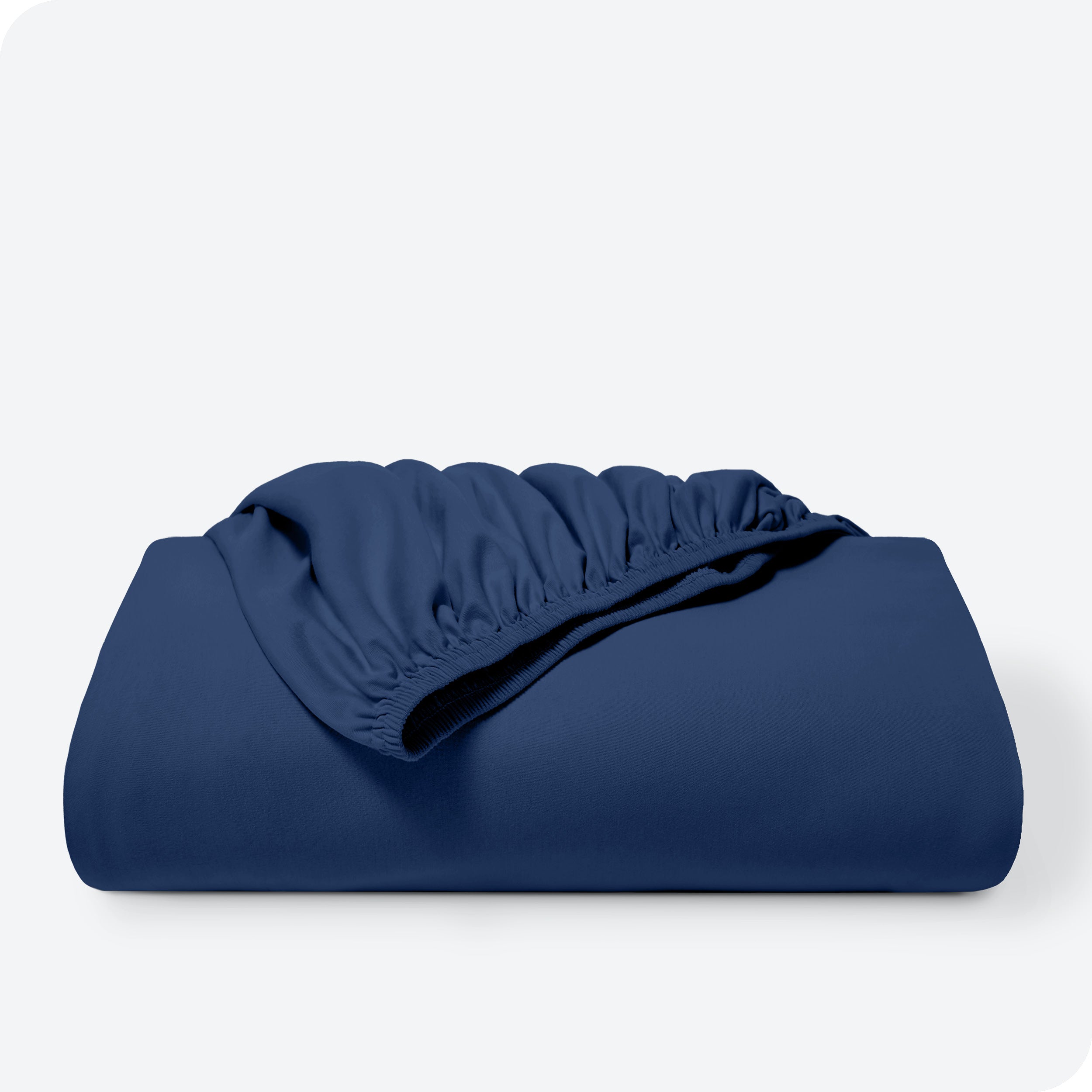 A bed made with a cotton jersey fitted sheet with 2 pillows near the headboard