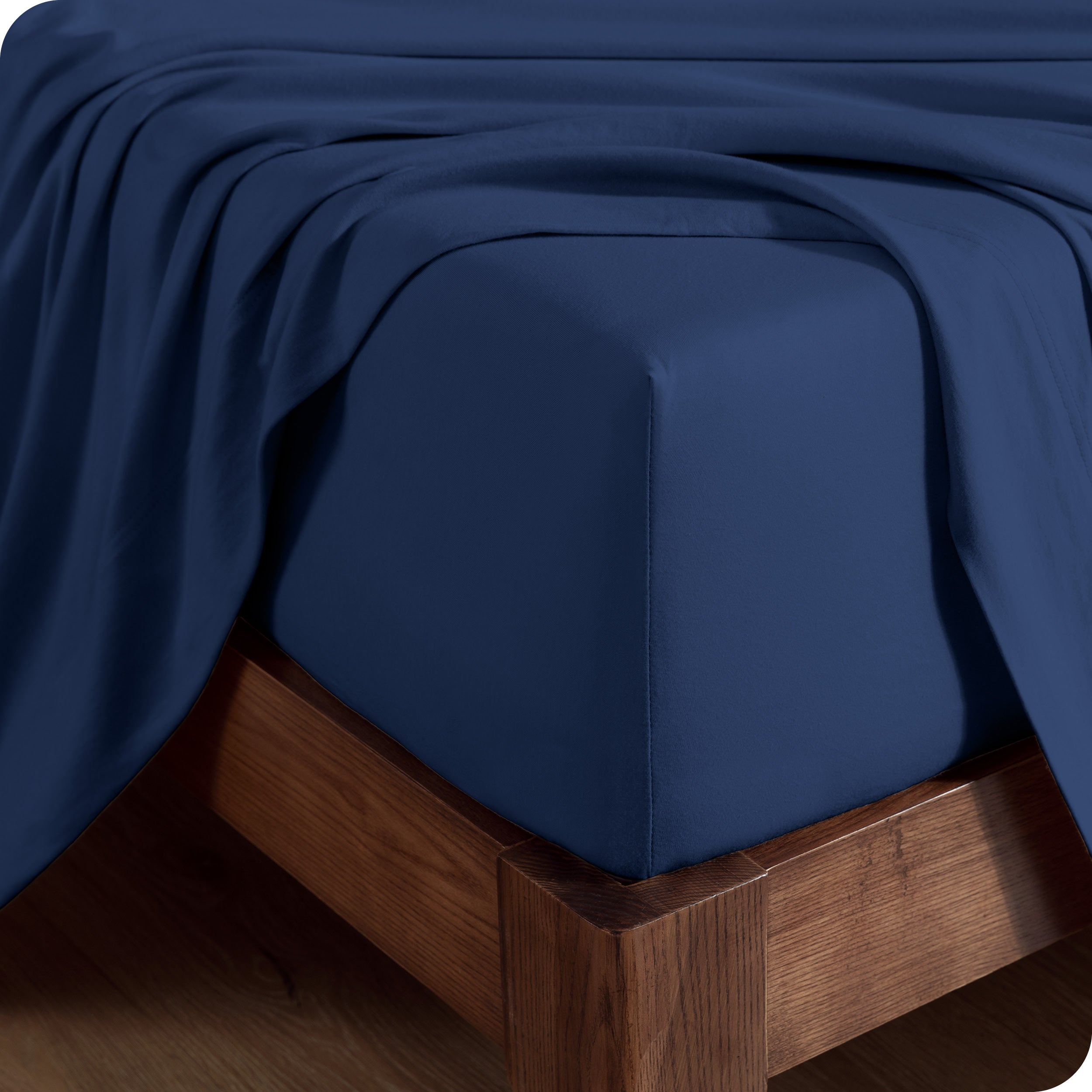 Close up of the corner of a mattress with a fitted sheet and flat sheet on it
