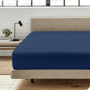 A percale fitted sheet on a bed with table next to it