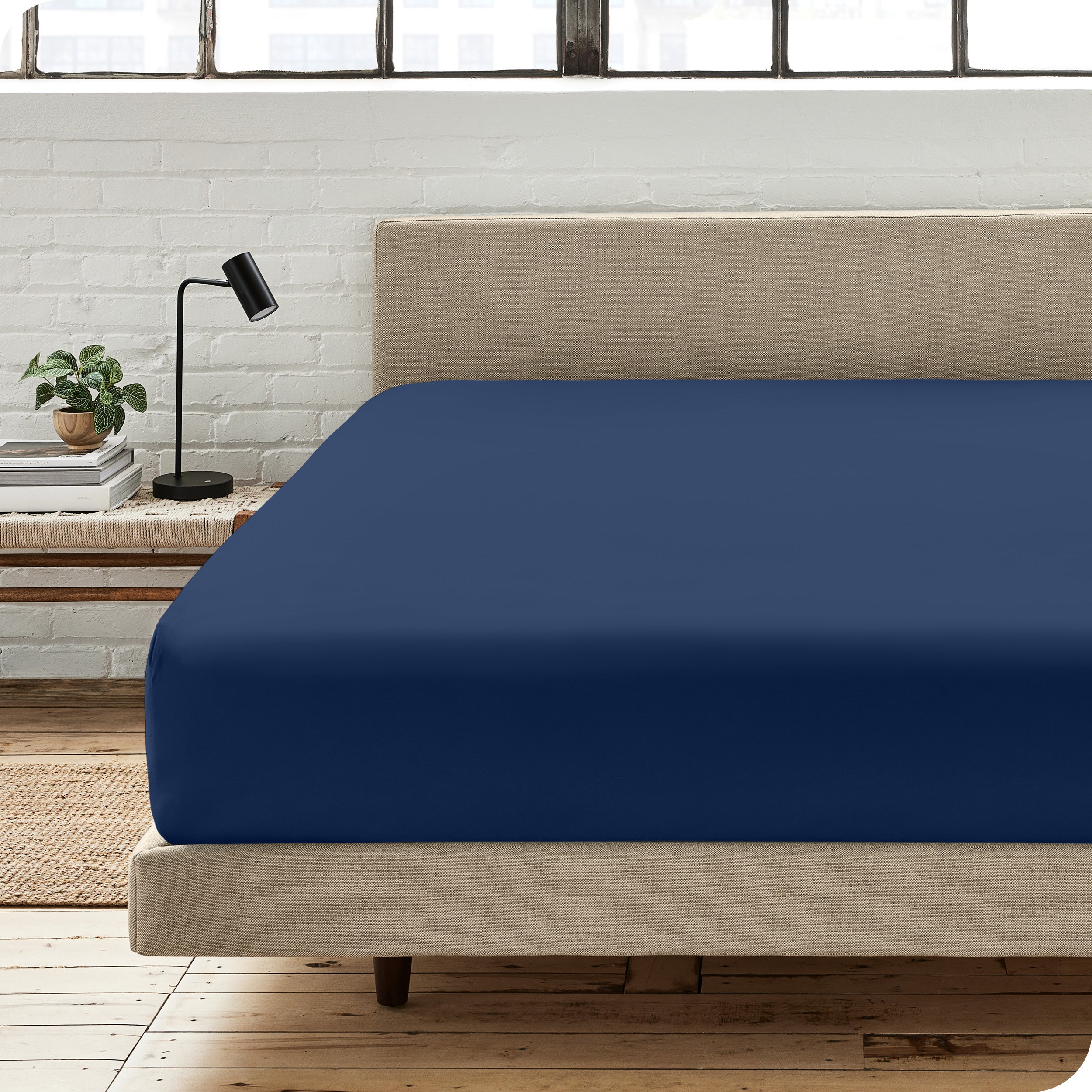 A percale fitted sheet on a bed with table next to it