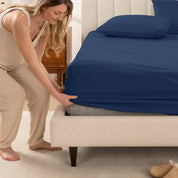 A women is putting on the percale fitted sheet on the bed