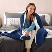 Woman cuddling with a sherpa blanket while sitting on the end of a bed