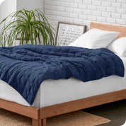 A cotton weighted blanket is loosely draped over a bed