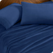 Two pillows with pillowcases on them set on a bed with matching sheets