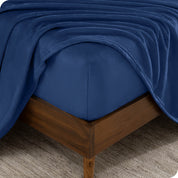 A corner of a mattress with a fitted sheet and a flat sheet on it.