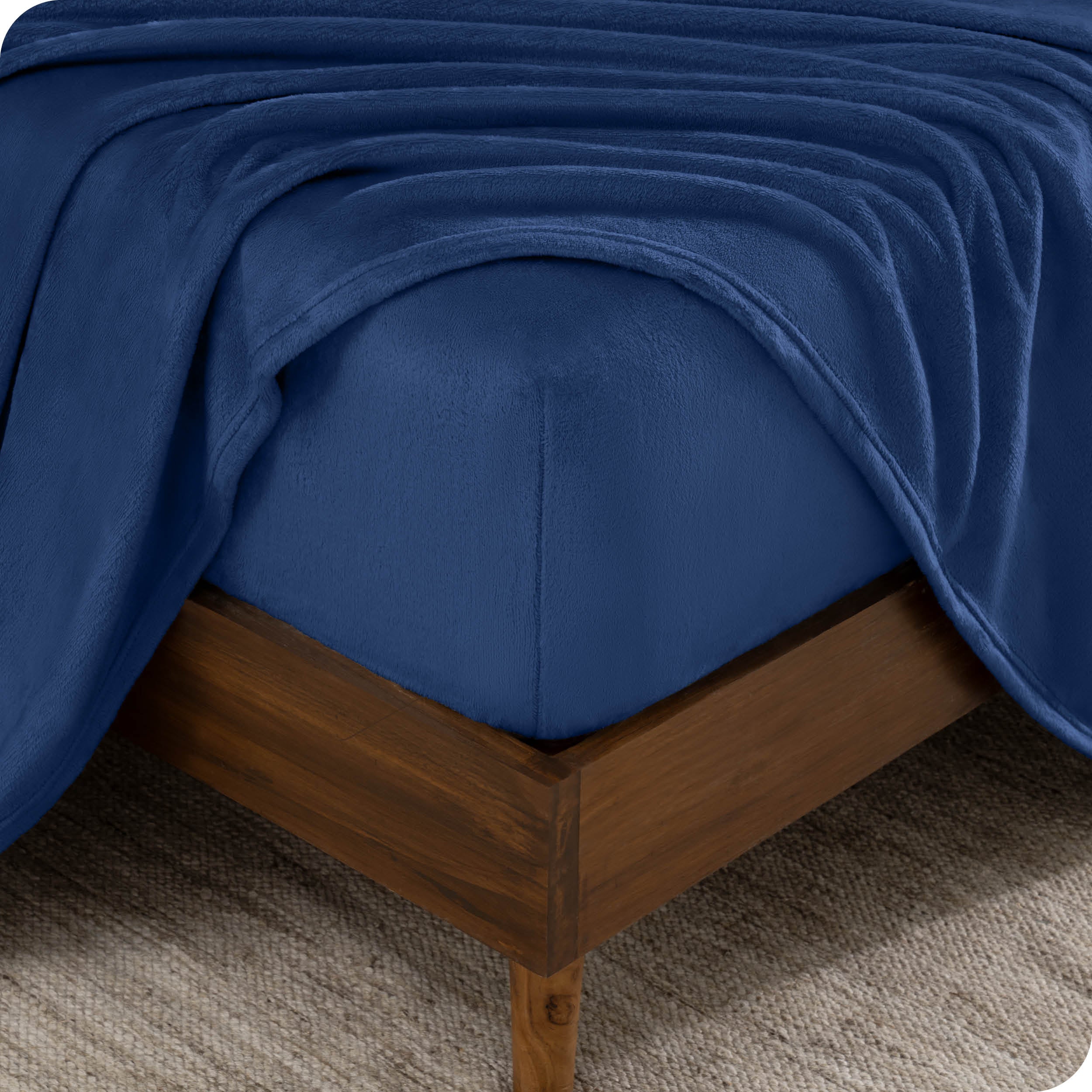 A corner of a mattress with a fitted sheet and a flat sheet on it.