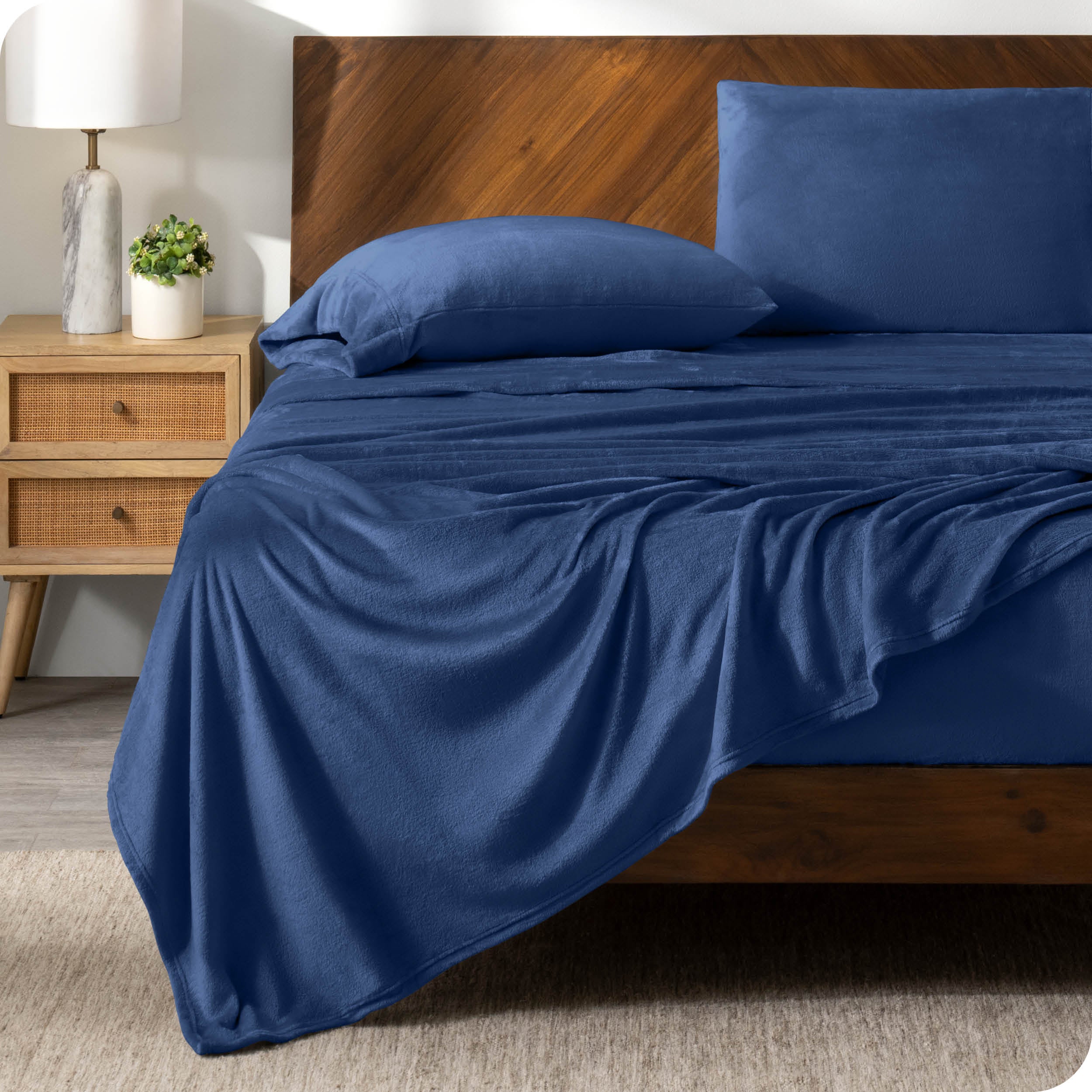A dark blue sheet set on a bed with a wooden bed frame