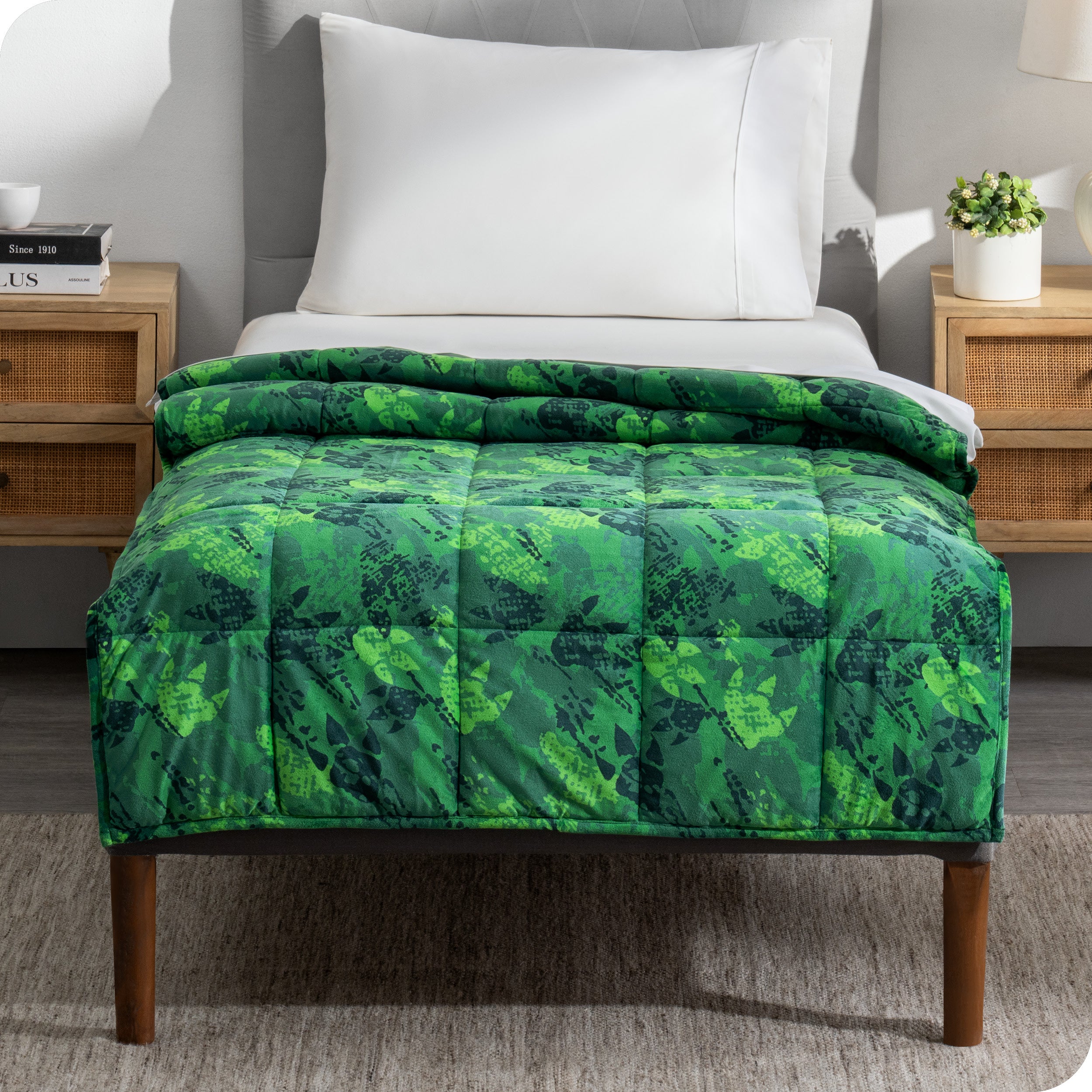 A printed weighted blanket hanging off the end of a twin size bed