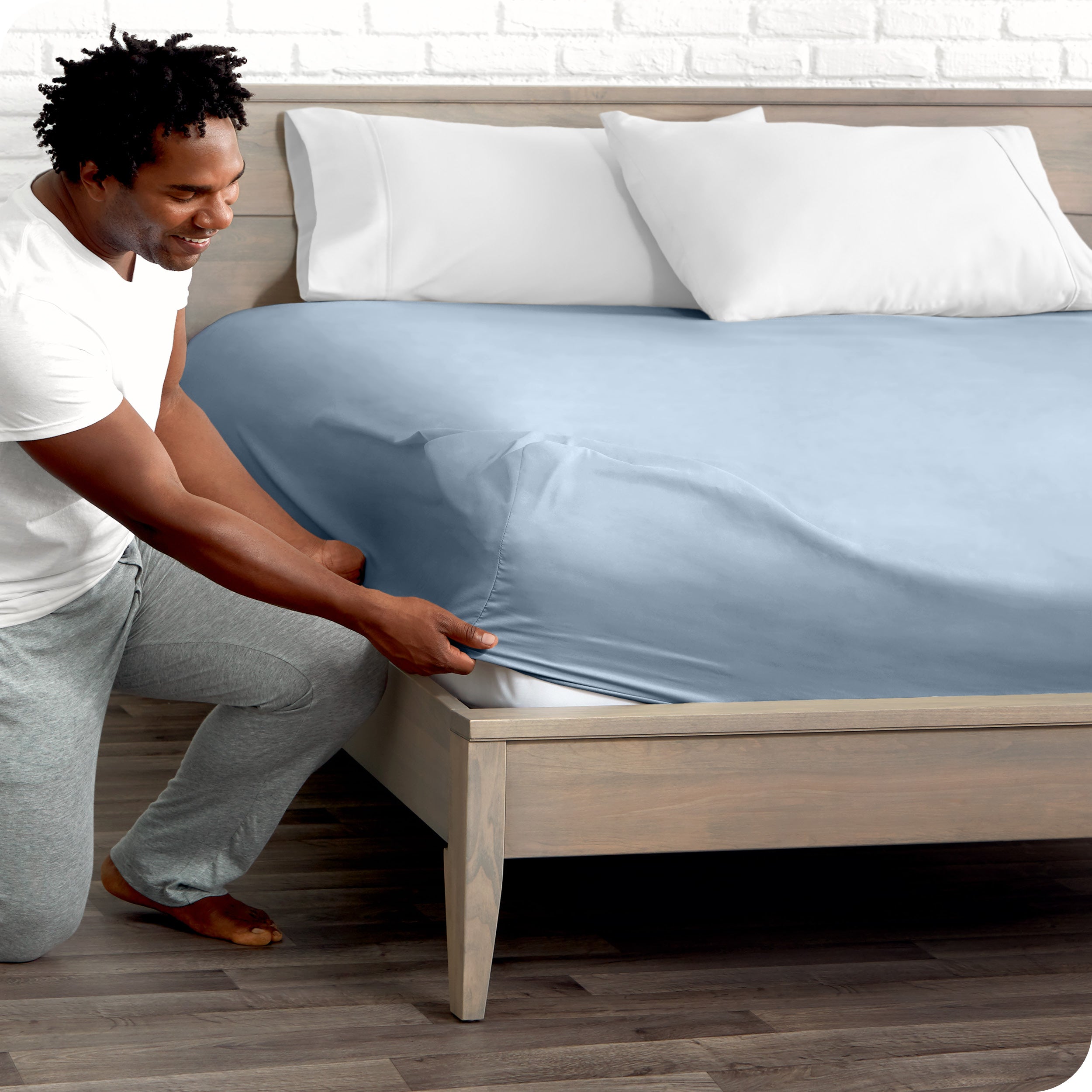 A man putting the microfiber fitted sheet on a mattress. 