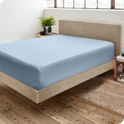 Corner view of a modern bed with a microfiber fitted sheet on the mattress. 