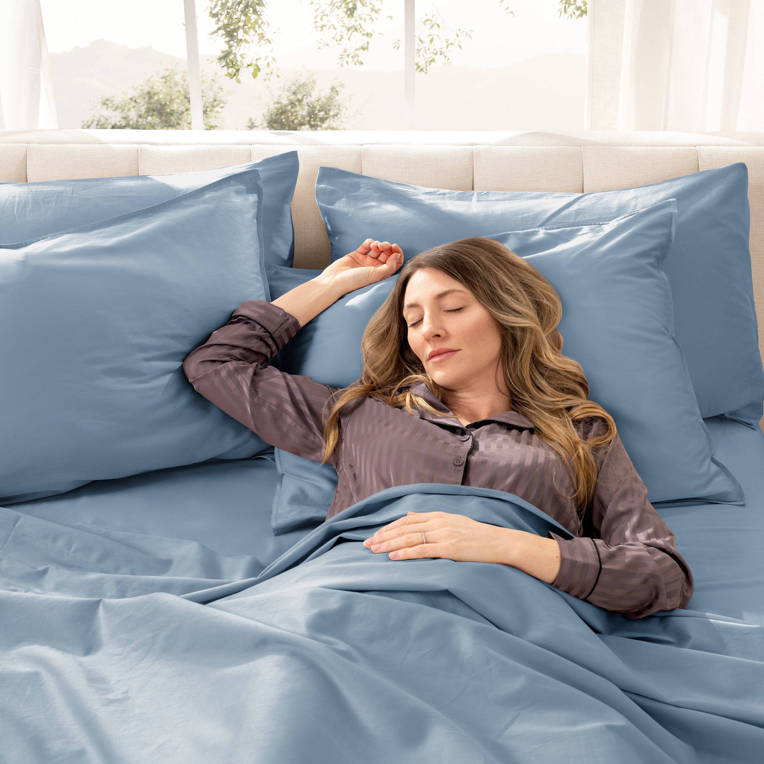 A woman sleeping on a bed made with organic cotton sateen sheets and pillowcases