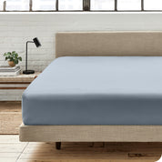 A percale fitted sheet on a bed with table next to it