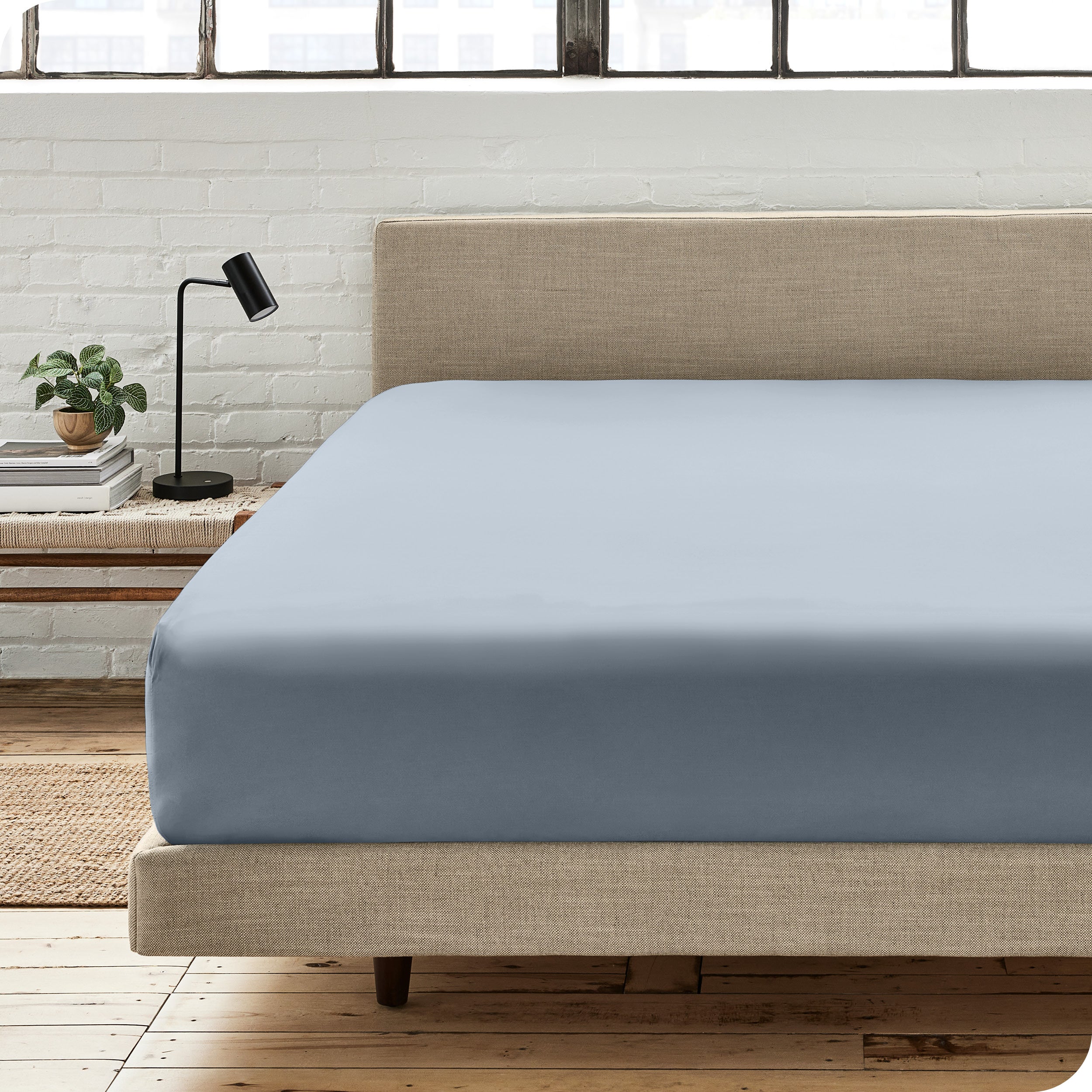 A percale fitted sheet on a bed with table next to it