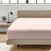A percale fitted sheet on a bed with table next to it