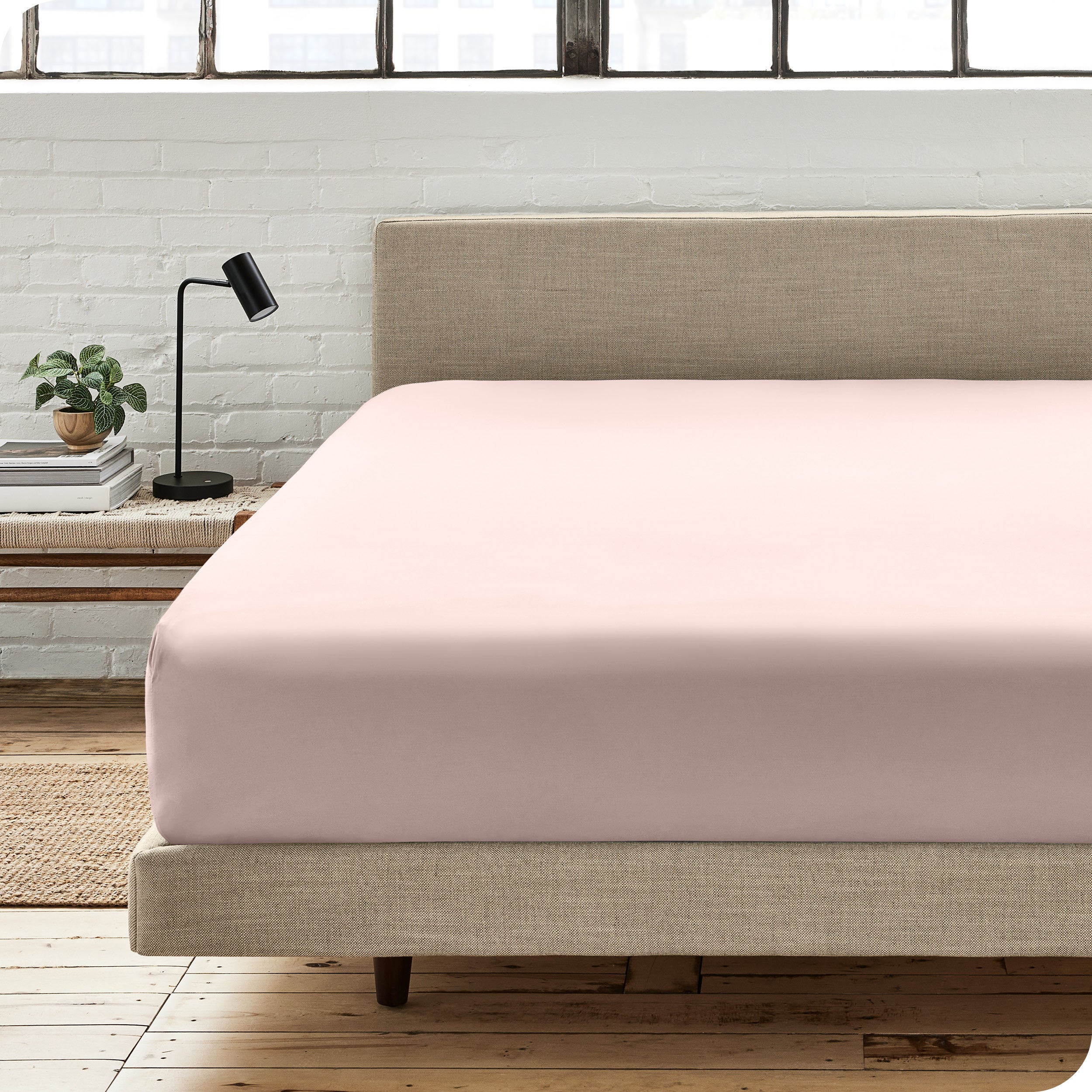 A percale fitted sheet on a bed with table next to it
