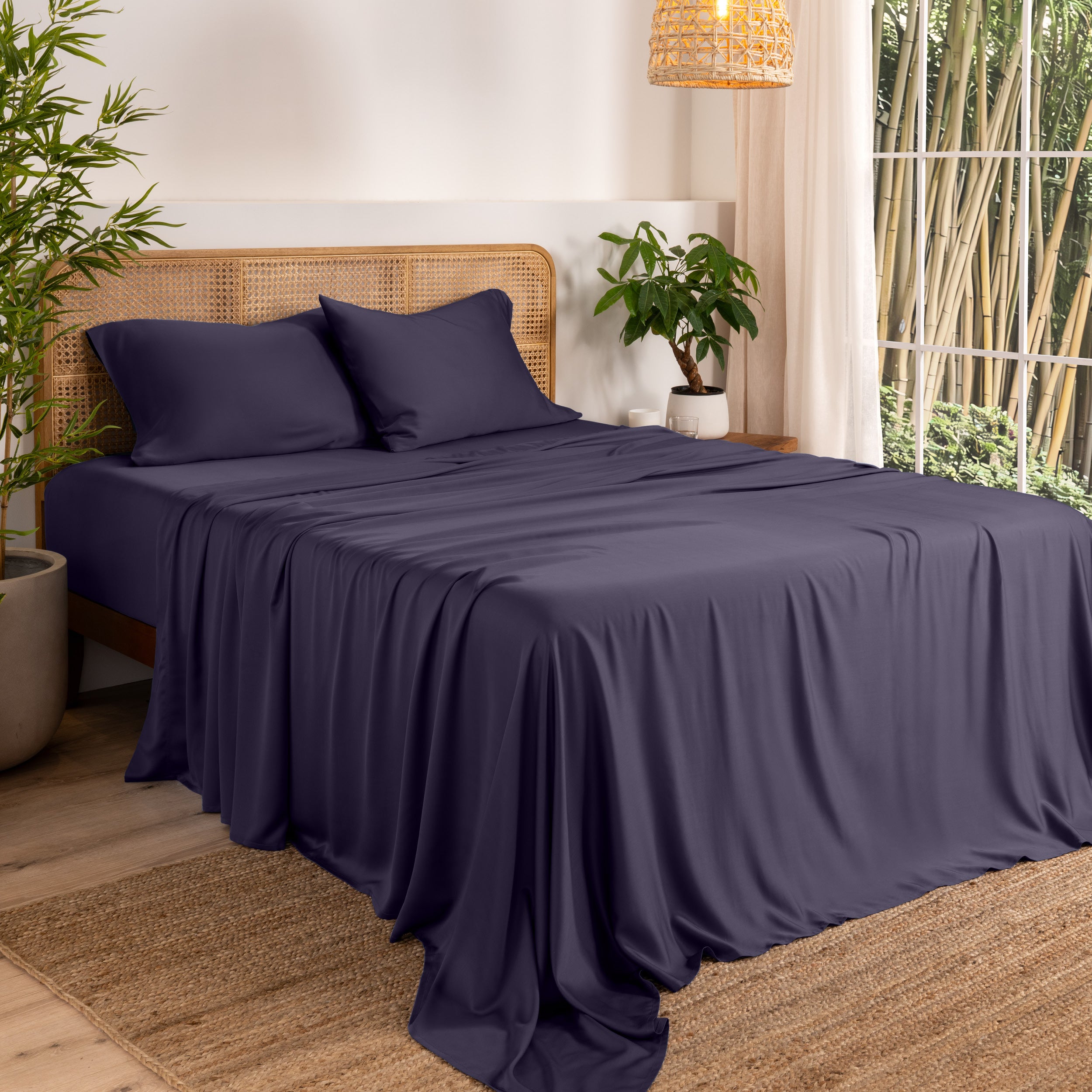 Bamboo sheets on a bed in a bedroom with plants and a window.