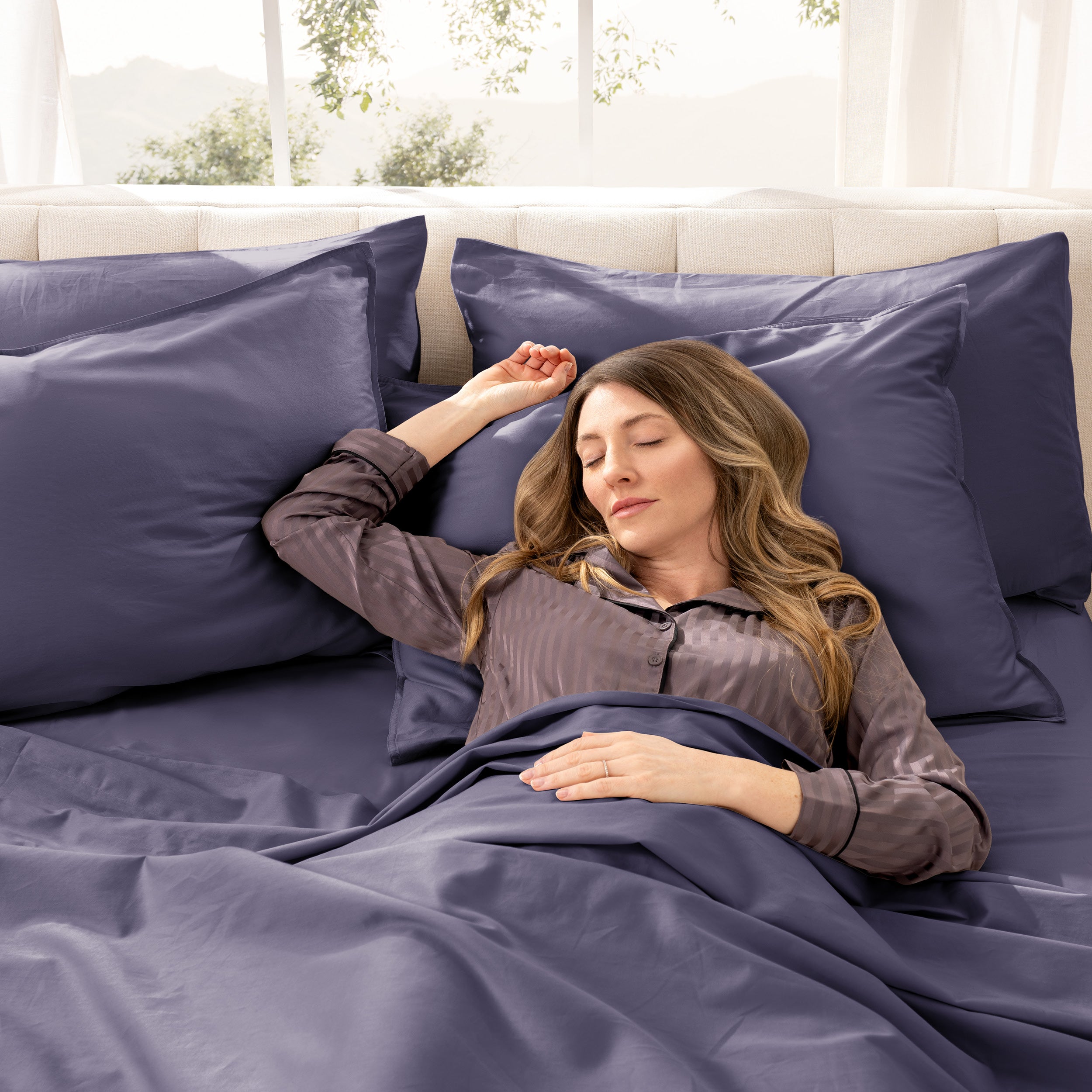 A woman sleeping on a bed made with organic cotton sateen sheets and pillowcases