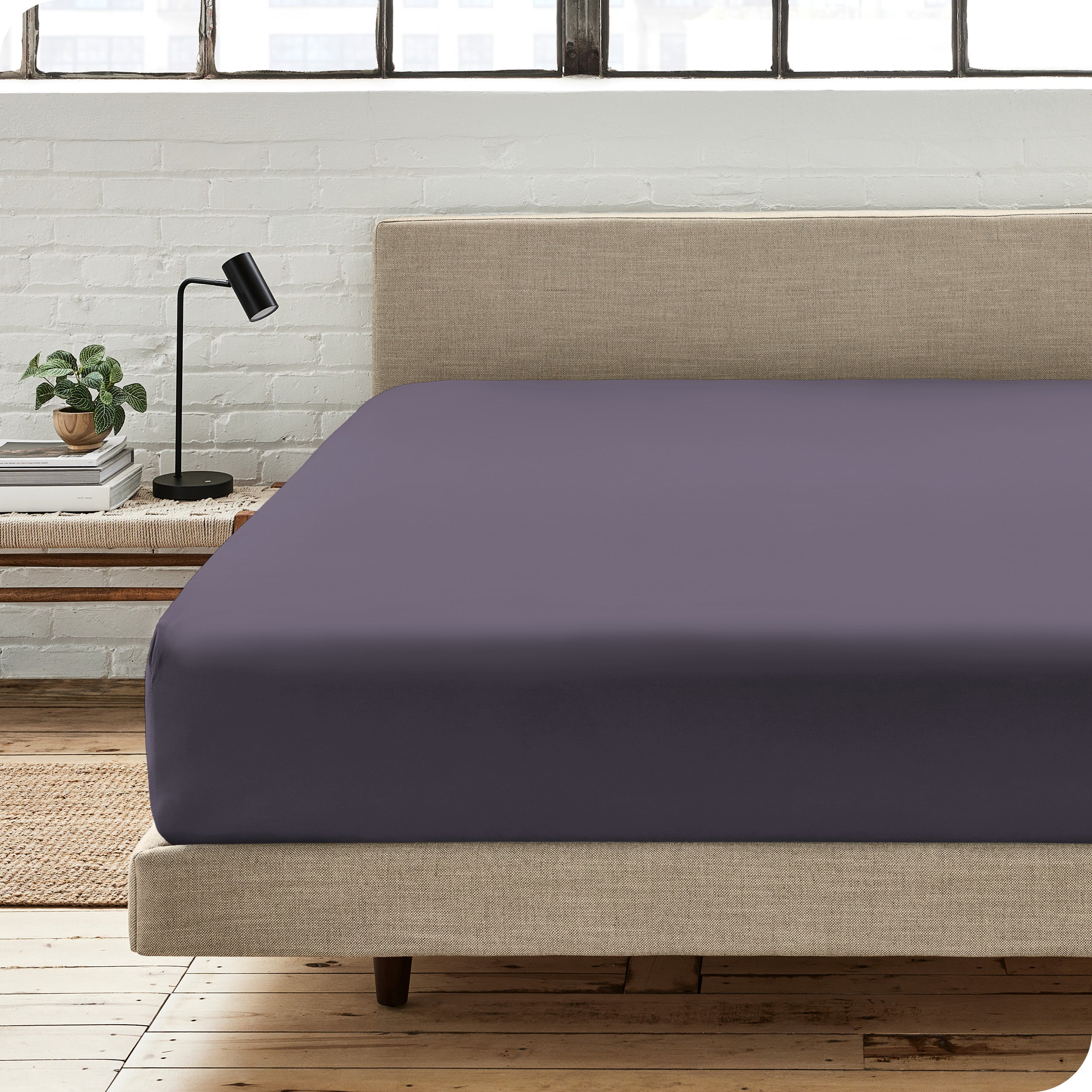 A percale fitted sheet on a bed with table next to it