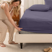 A women is putting on the percale fitted sheet on the bed