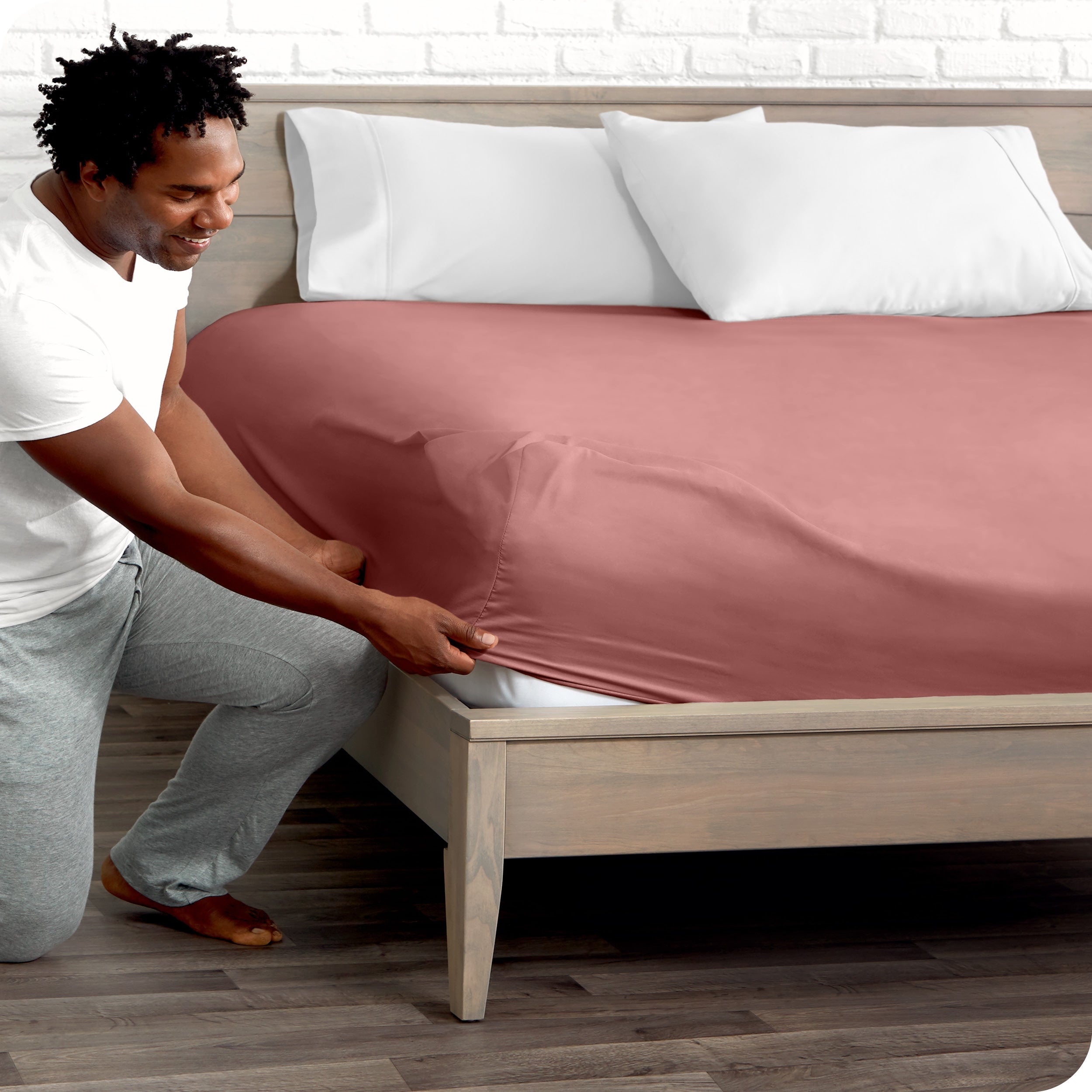 A man putting the microfiber fitted sheet on a mattress. 