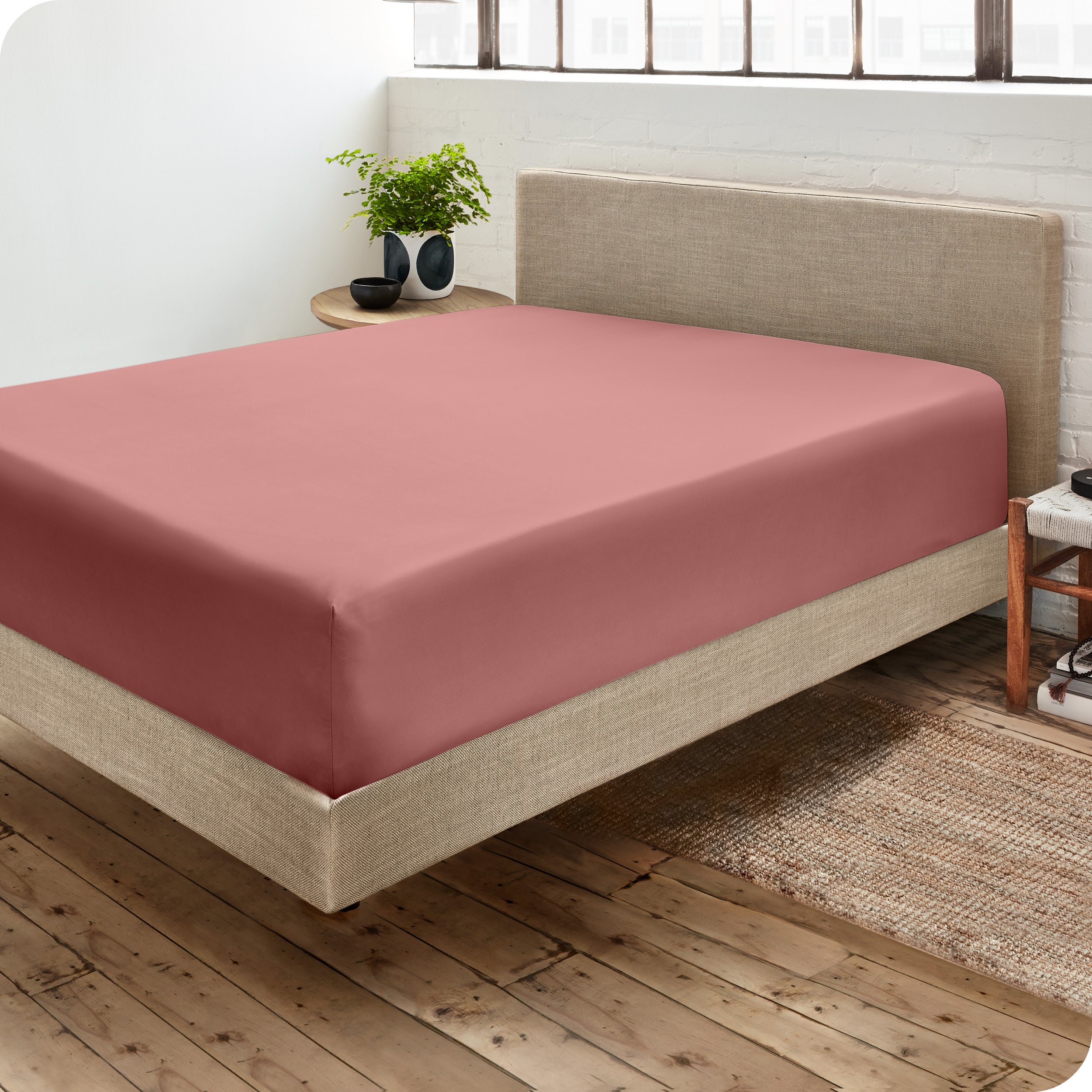 Corner view of a modern bed with a microfiber fitted sheet on the mattress. 