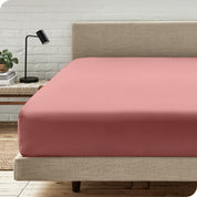 A bed with a microfiber fitted sheet on the mattress. 