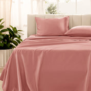 Organic sateen bedding on a bed with a beige headboard and plant in the corner.