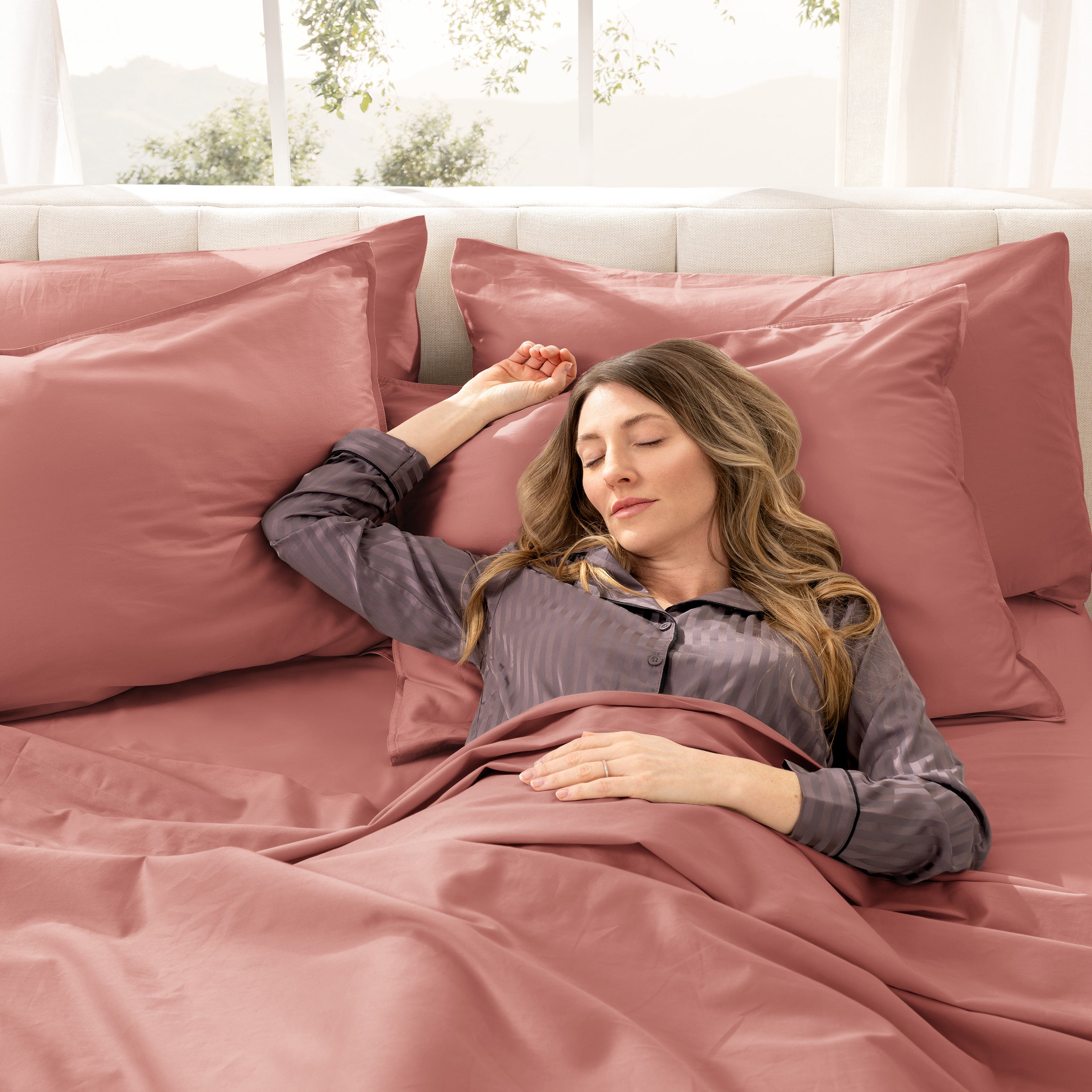 A woman sleeping on a bed made with organic cotton sateen sheets and pillowcases