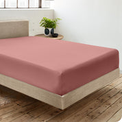 A percale fitted sheet on a bed with table next to it