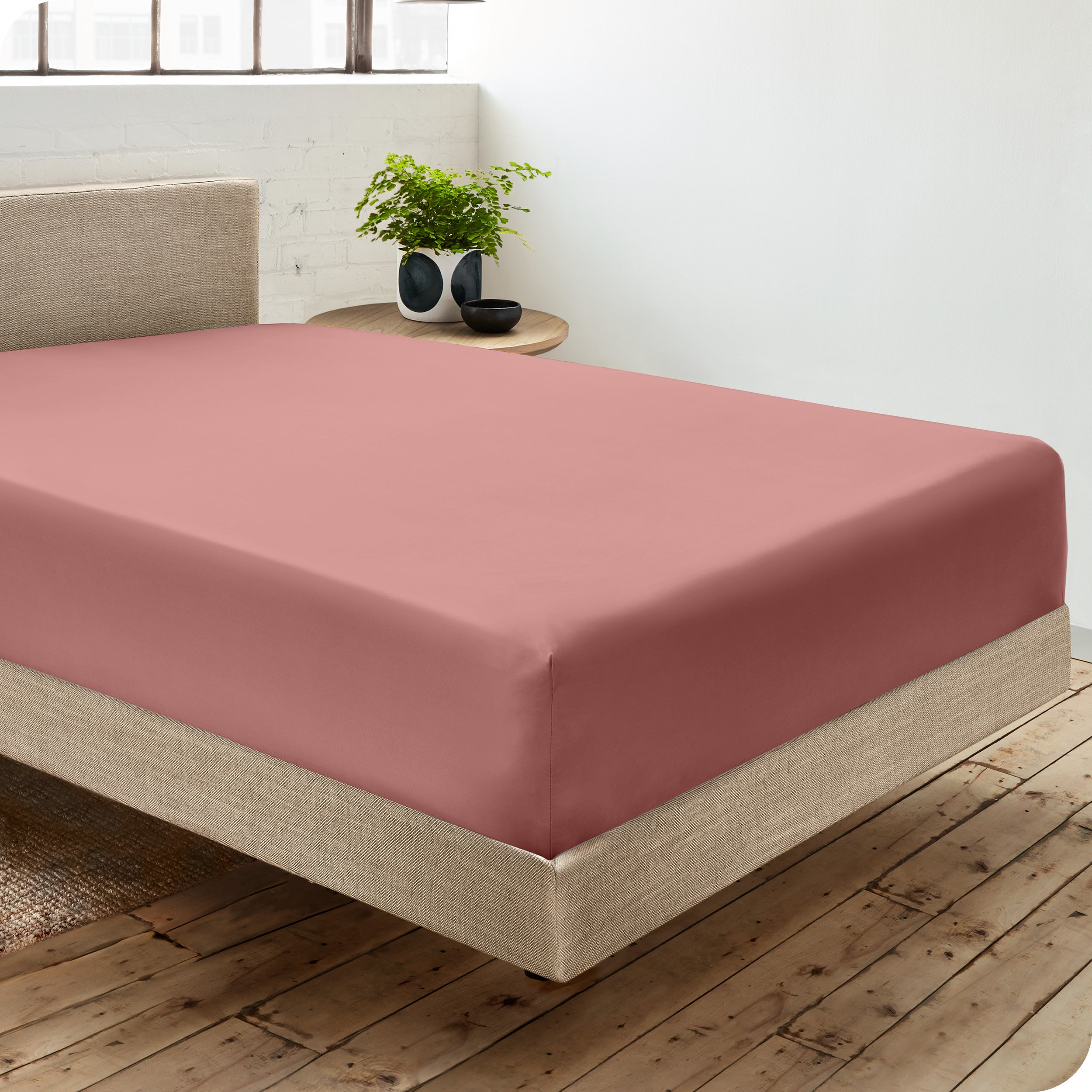 A percale fitted sheet on a bed with table next to it