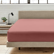 A percale fitted sheet on a bed with table next to it