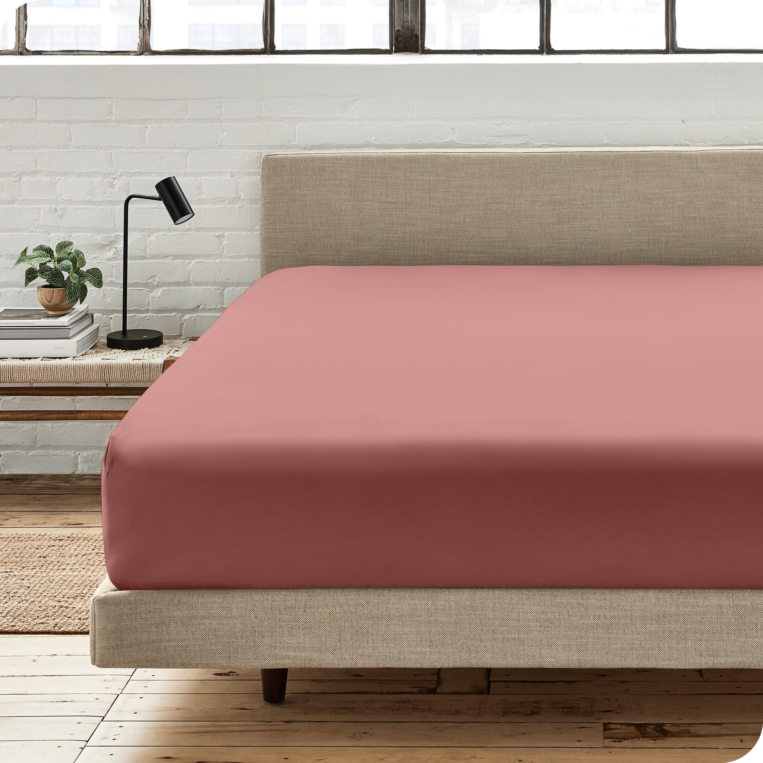 A percale fitted sheet on a bed with table next to it