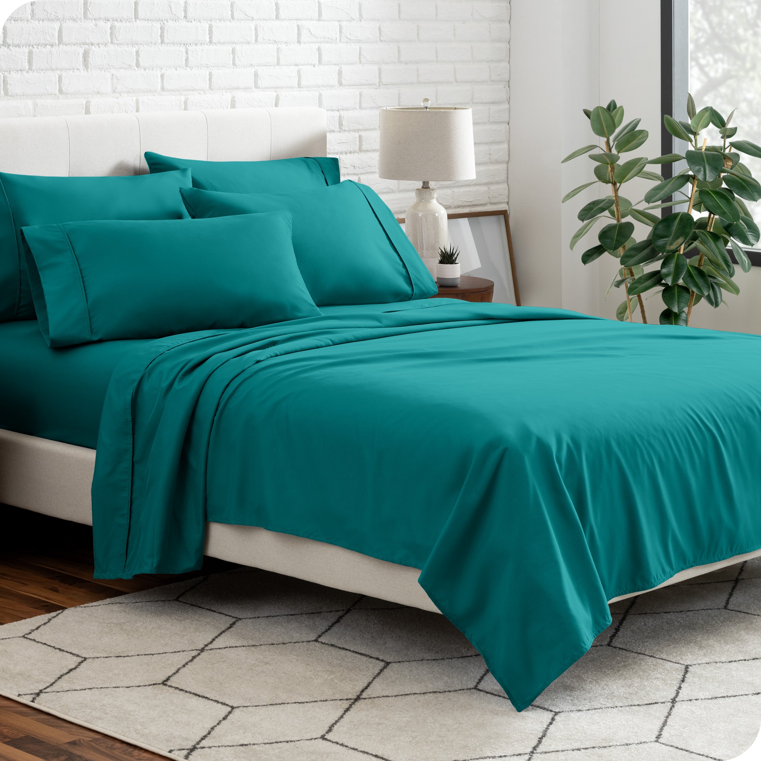 A bedroom setting with a bed made with the microfiber bed sheets and four pillows.