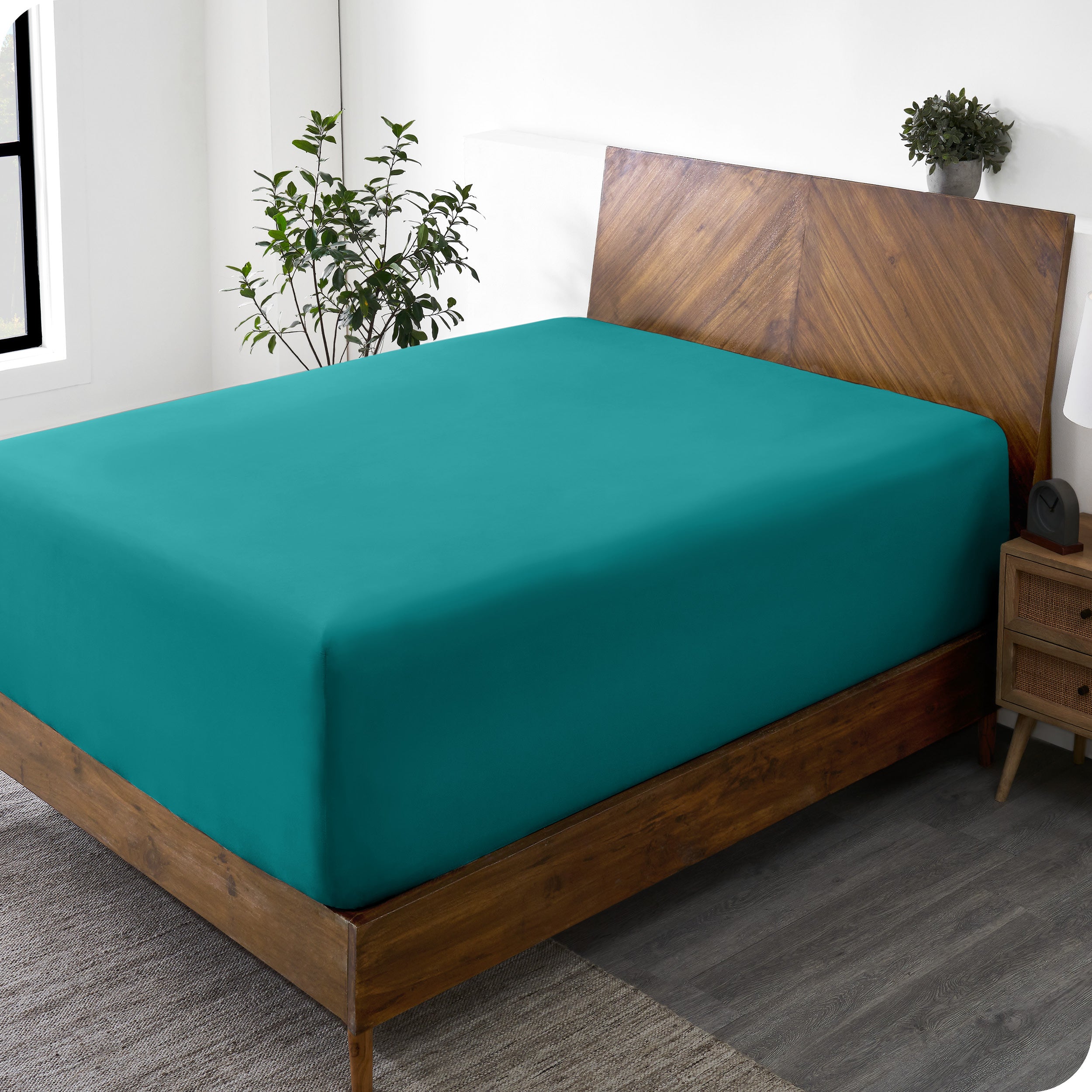 A wide corner view of a modern bed made with a microfiber fitted sheet on the mattress. 