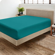 Corner view of a modern bed with a microfiber fitted sheet on the mattress. 