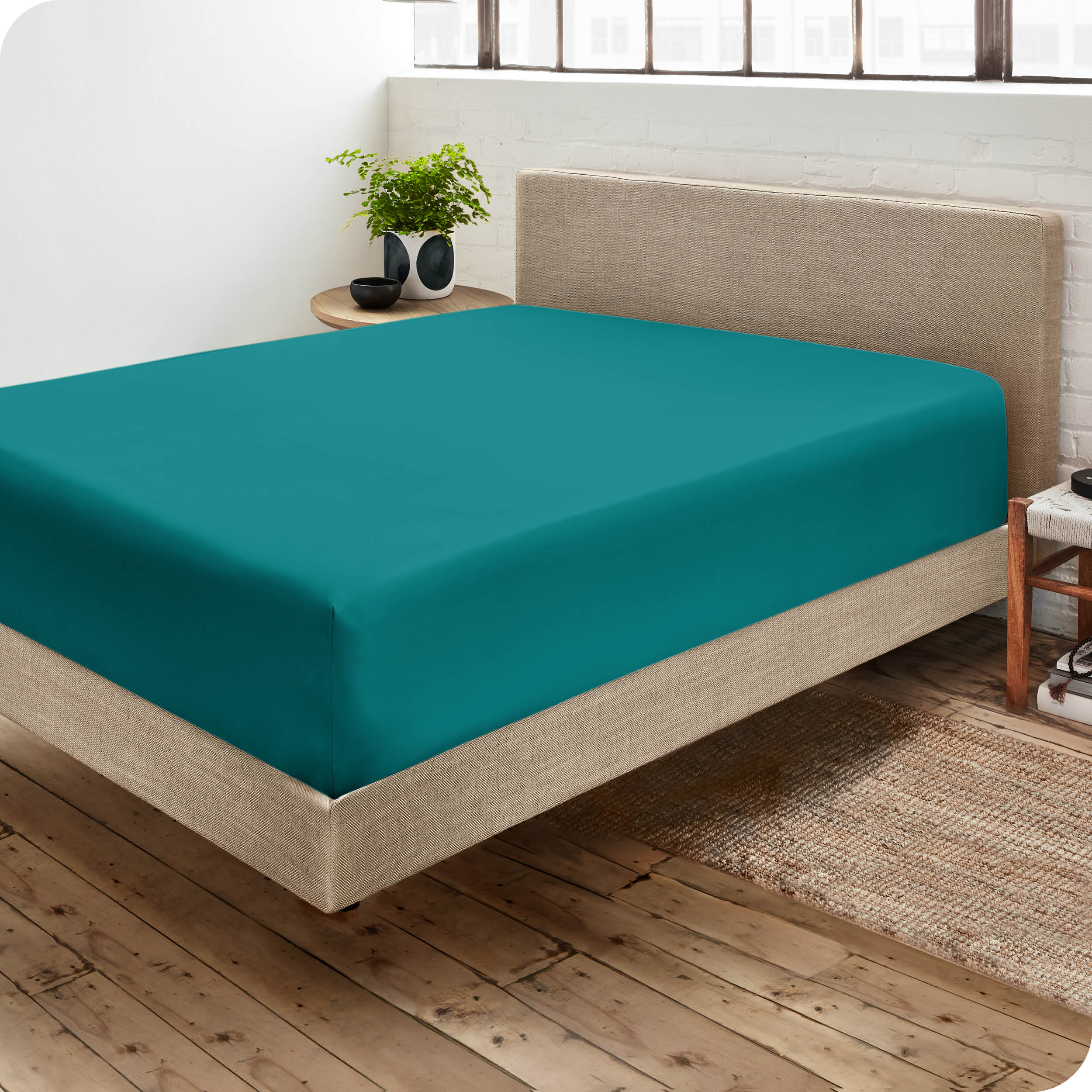 Corner view of a modern bed with a microfiber fitted sheet on the mattress. 