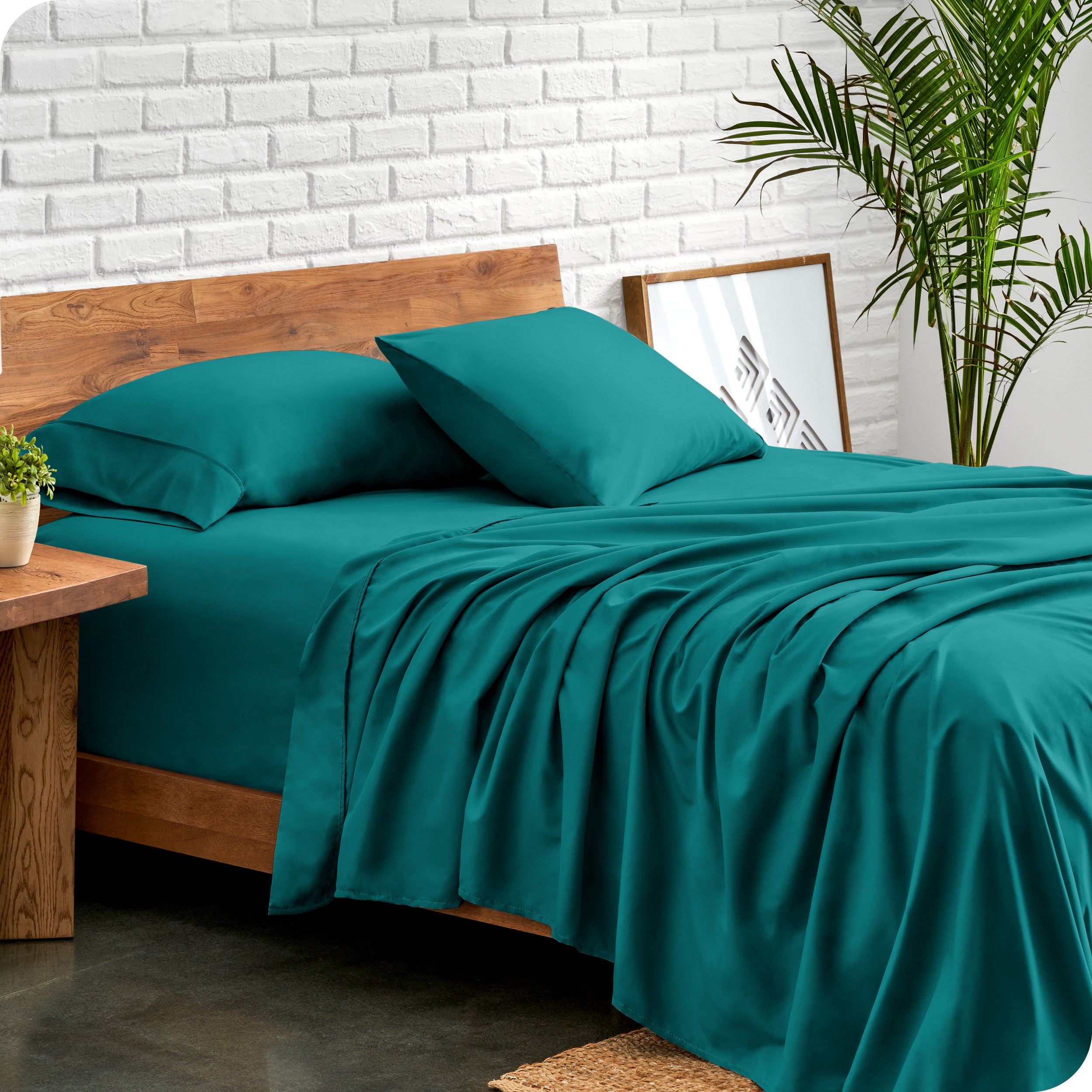Microfiber sheets and matching pillowcases on a bed next to a large plant